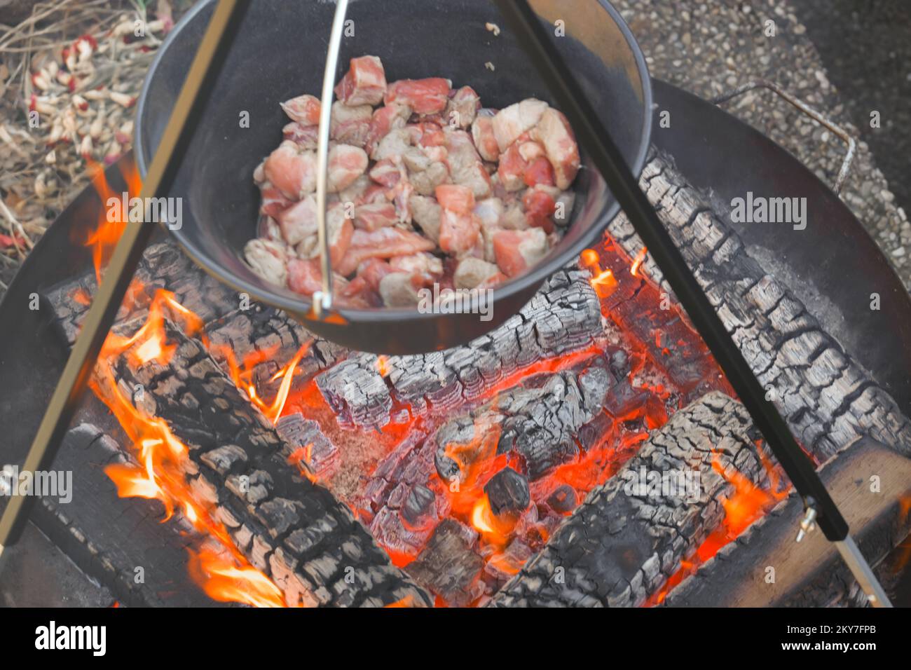 Carne in un calderone su carbone bruciante background.food sul fuoco. Cucinare carne in un cauldron.Street food .Camping cooking.Wood fuoco e cauldron con Foto Stock