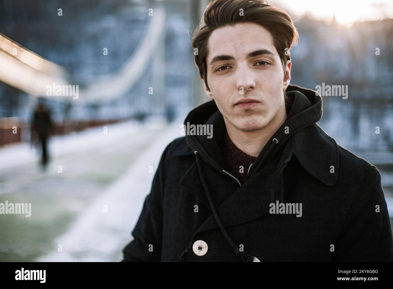 Ritratto di un ragazzo fiducioso hipster in piedi sul ponte guardando la fotocamera Foto Stock