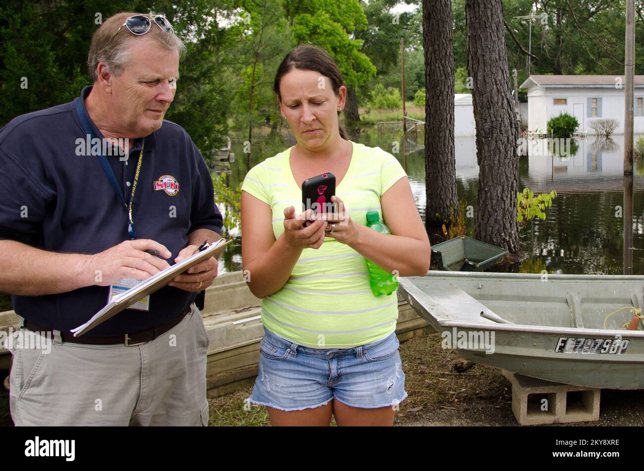 Pensacola, Florida, 12 maggio 2014 durante una valutazione dei danni a Jackson County, Florida, membro del team di risposta alle emergenze statali (SERT), Alvin Bishop guarda le foto della casa danneggiata dall'alluvione di Brandy Dudley. La pioggia torrenziale da un paio di tempeste ha innescato una grande inondazione di flash lungo parti del Florida Panhandle. Andrea Booher/FEMA. Florida forti tempeste, tornado, venti in linea retta e alluvioni. Fotografie relative a disastri e programmi, attività e funzionari di gestione delle emergenze Foto Stock