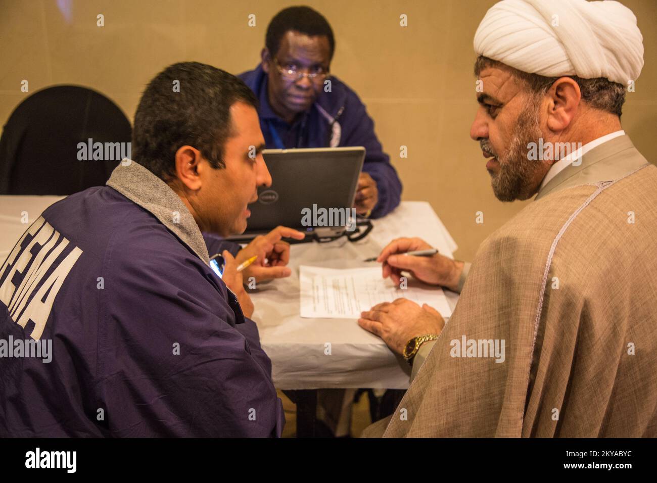 Dearborn, MI, 17 ottobre 2014 - Mohsin Mahmood (a sinistra), FEMA Individual Assistance (IA) Coordinatore di collegamento ed eventi speciali, aiuta i sopravvissuti alle catastrofi Kassem Baydoun (a destra, turbante bianco) registrarsi presso la FEMA presso un sito di supporto al recupero (RSS) presso il Centro Islamico d'America di Dearborn, Michigan in risposta alle gravi tempeste e alluvioni del 11-13 agosto 2014 che hanno colpito negativamente le contee del Michigan di Wayne, Oakland e Macomb. La FEMA sostiene i governi locali e statali e le entità tribali nei loro sforzi per riprendersi dalle catastrofi naturali. Michigan forti tempeste e inondazioni. Fotograp Foto Stock
