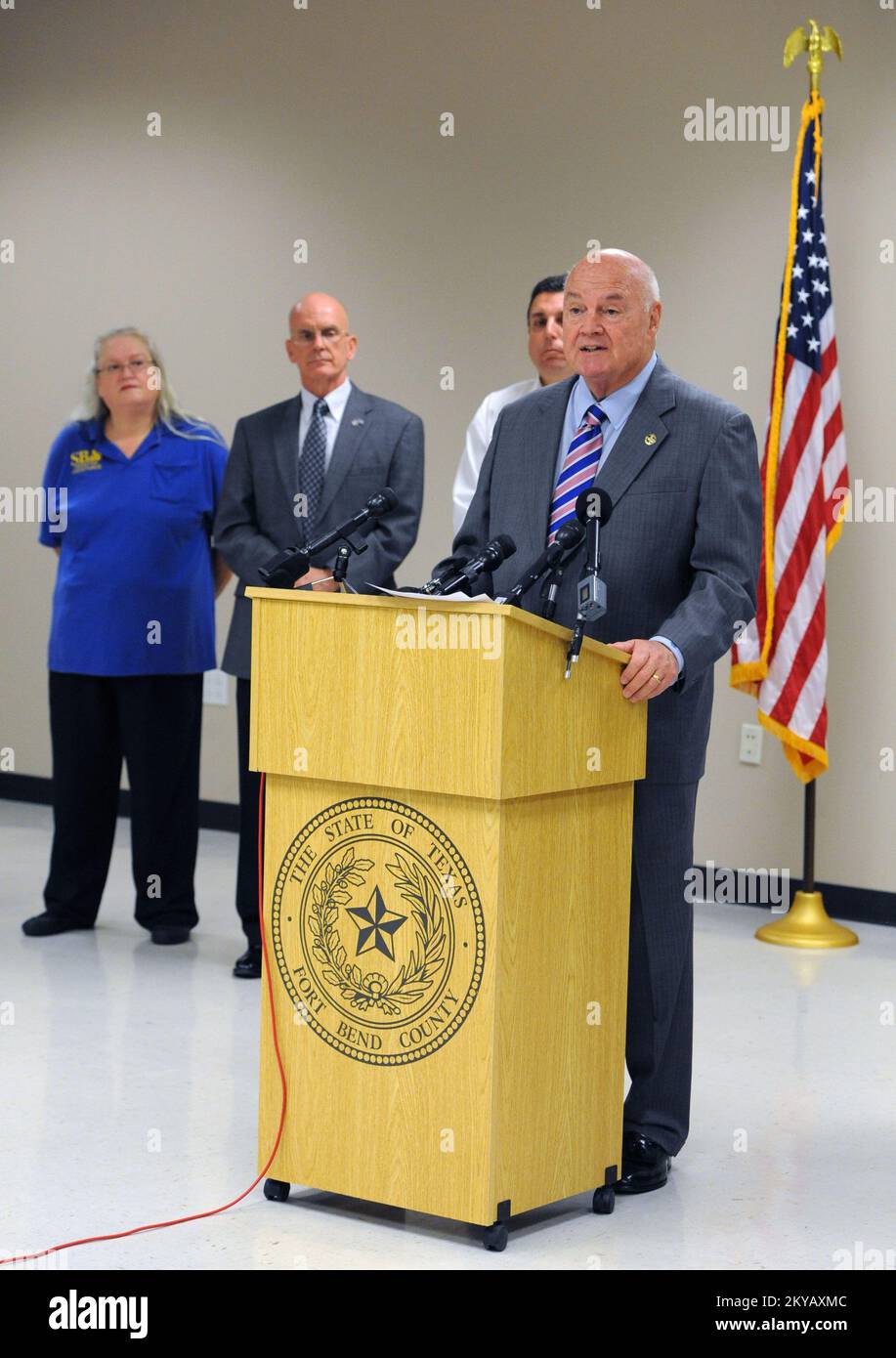 Rosenberg, TX, USA-15 giugno 2015 il giudice della contea di Fort Bend Bob Hebert (all'odium) annuncia l'apertura di un Mobile Registration Intake Center presso l'annesso Rosenberg. A Hebert hanno partecipato funzionari locali, nazionali, statali e federali. Jocelyn. Rosenberg, TX, USA-15 giugno 2015--il giudice della contea di Fort Bend Bob Hebert (sul podio) annuncia l'apertura di un centro di entrate per la registrazione mobile presso l'annesso Rosenberg. A Hebert si unirono funzionari locali, nazionali, statali e federali. Fotografie relative a disastri e programmi, attività e funzionari di gestione delle emergenze Foto Stock