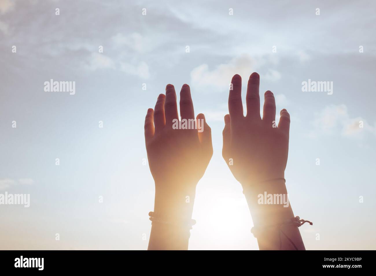 Le mani delle donne alzate davanti al tramonto Foto Stock