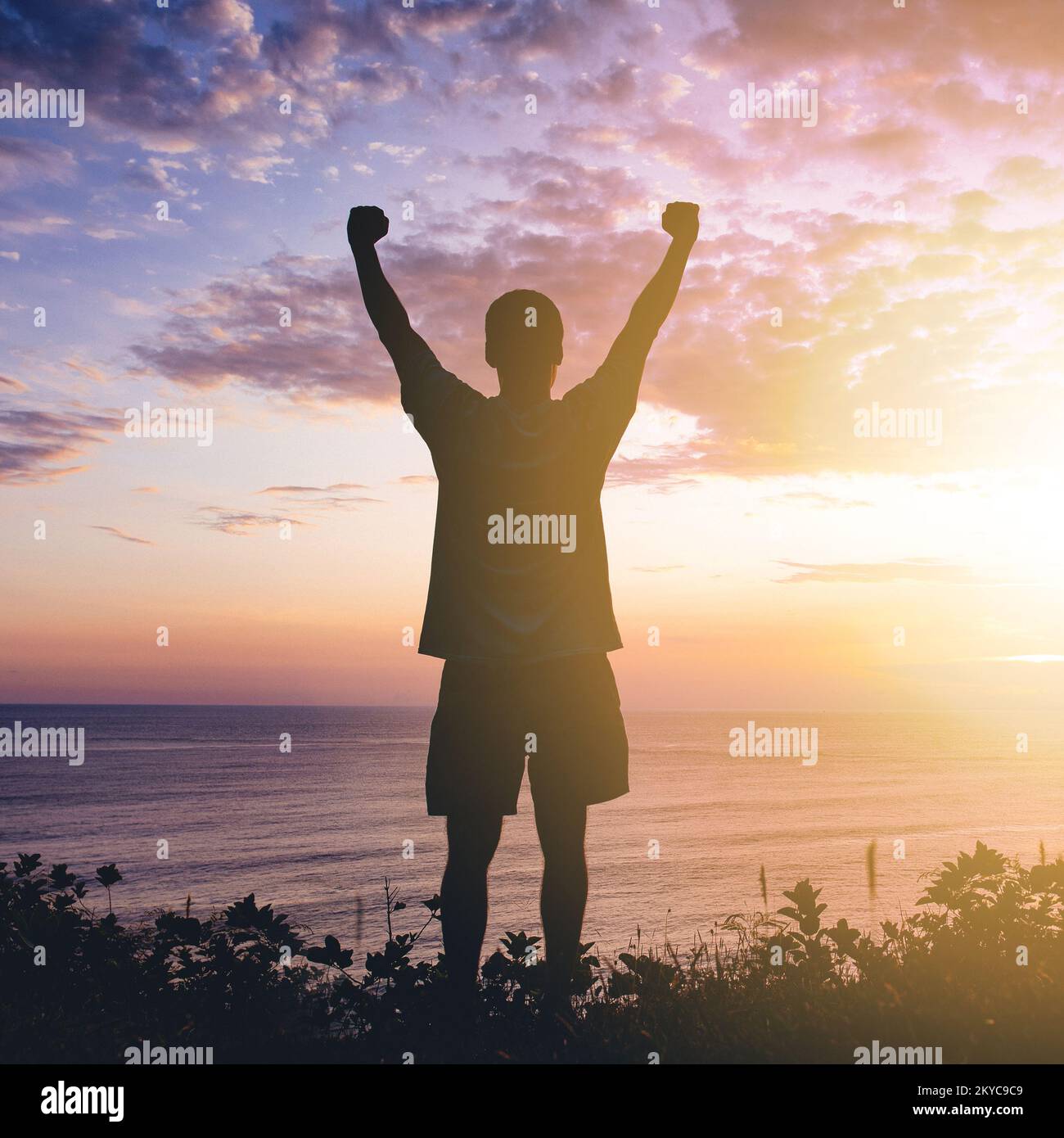 L'uomo che alza i pugni sul cielo del tramonto Foto Stock