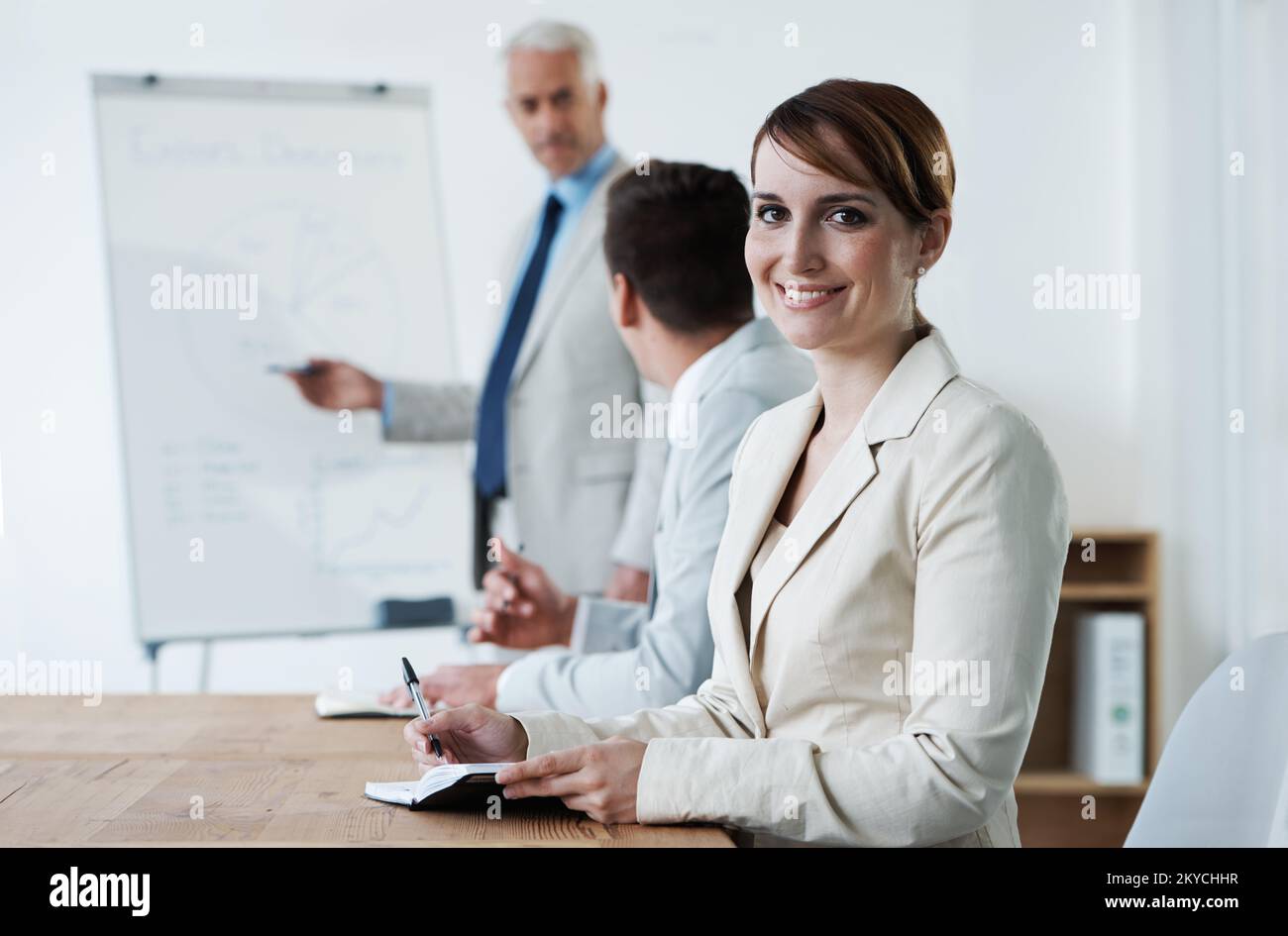 Shes ha ottenuto il bordo corporativo. Gli uomini d'affari si sono riuniti intorno ad un tavolo mentre il loro manager dà una presentazione. Foto Stock