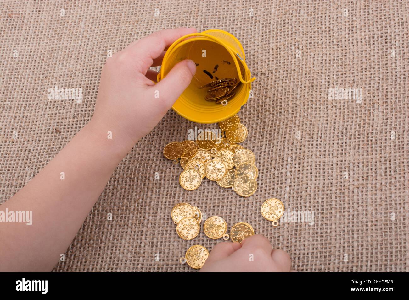 La benna e Falsificare monete d oro in mano su tela lo sfondo Foto Stock