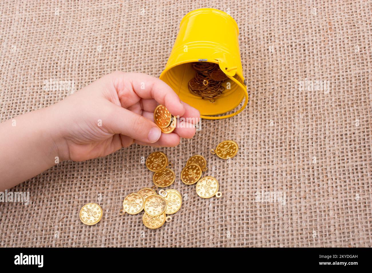 La benna e Falsificare monete d oro in mano su tela lo sfondo Foto Stock