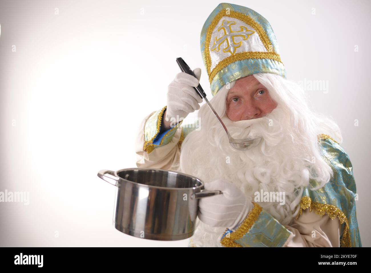 USA su sfondo bianco. Olandese Babbo Natale San Nicola capodanno San Nicholas con una pentola nelle sue mani preparando il cibo di cenone di Capodanno che fa pubblicità a Natale mangia il cibo con una paletta Foto Stock