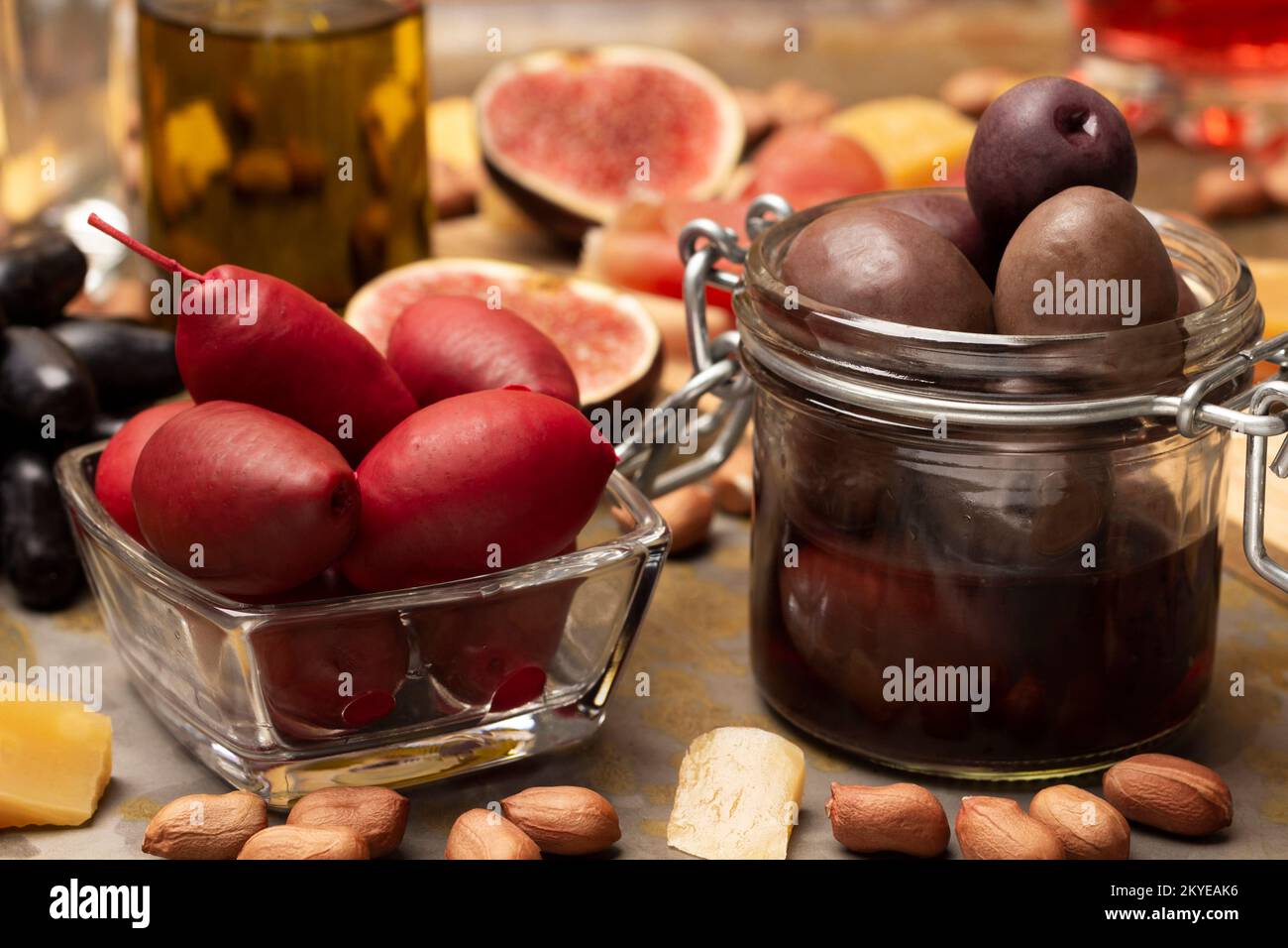 Olive rosse e marroni in una ciotola di vetro. Figure e dadi sulla tavola. Primo piano. Foto Stock