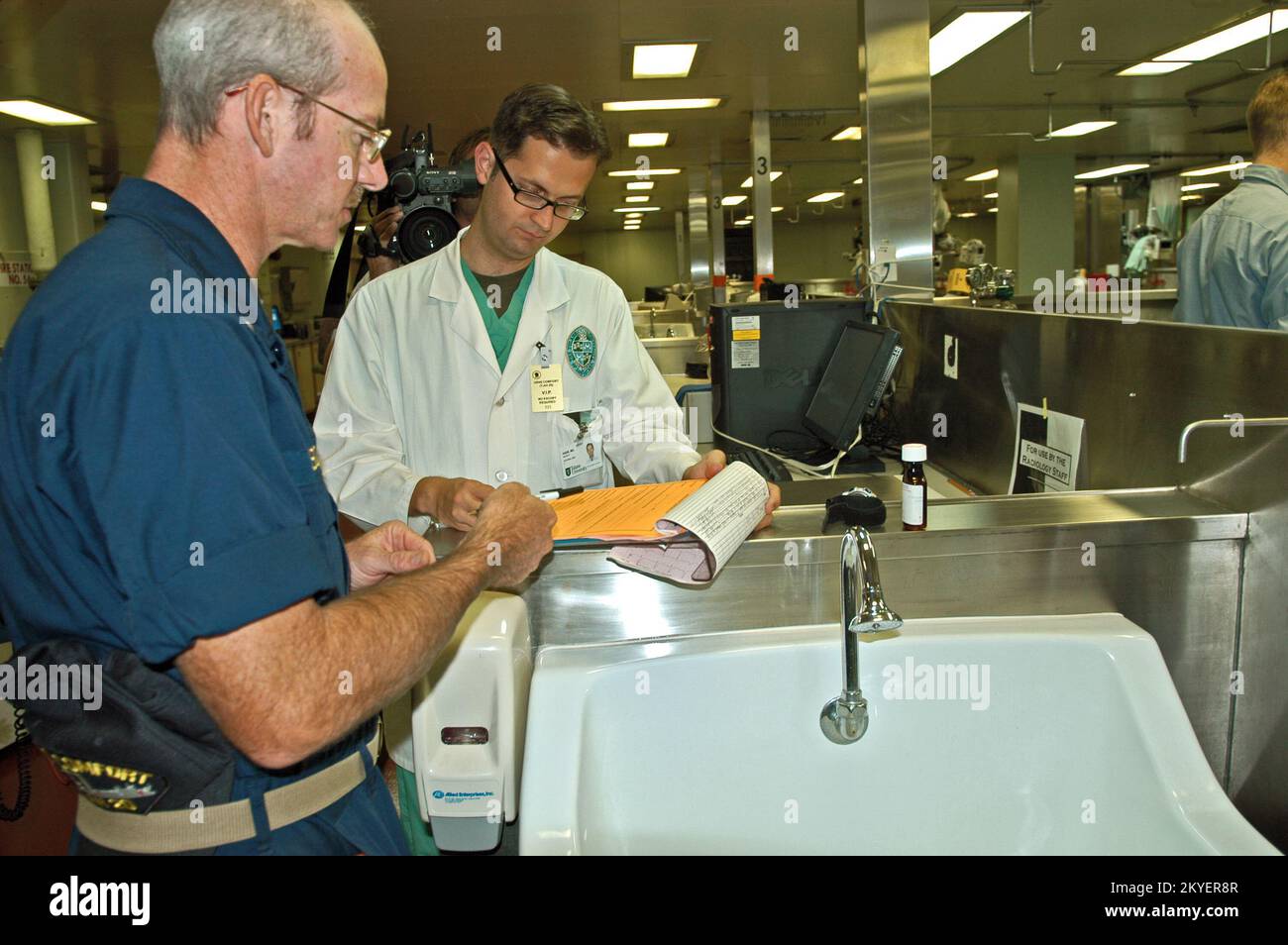 Hurricane Katrina/Hurricane Rita, New Orleans, 6 ottobre 2005 - Un corpsman della Marina (a sinistra) e un medico della Louisiana state University vanno sopra la cartella medica di un paziente ammesso sul Comfort USNS, Una nave ospedaliera ora ormeggiata qui per fornire sostegno alle strutture mediche della città che hanno subito danni paralizzanti causati dagli uragani Katrina e Rita. Il personale medico dell'Università sta aiutando a fornire il trattamento alle persone che hanno bisogno di cure mediche inviate a questa struttura medica galleggiante. Vinci Henderson/FEMA Foto Stock