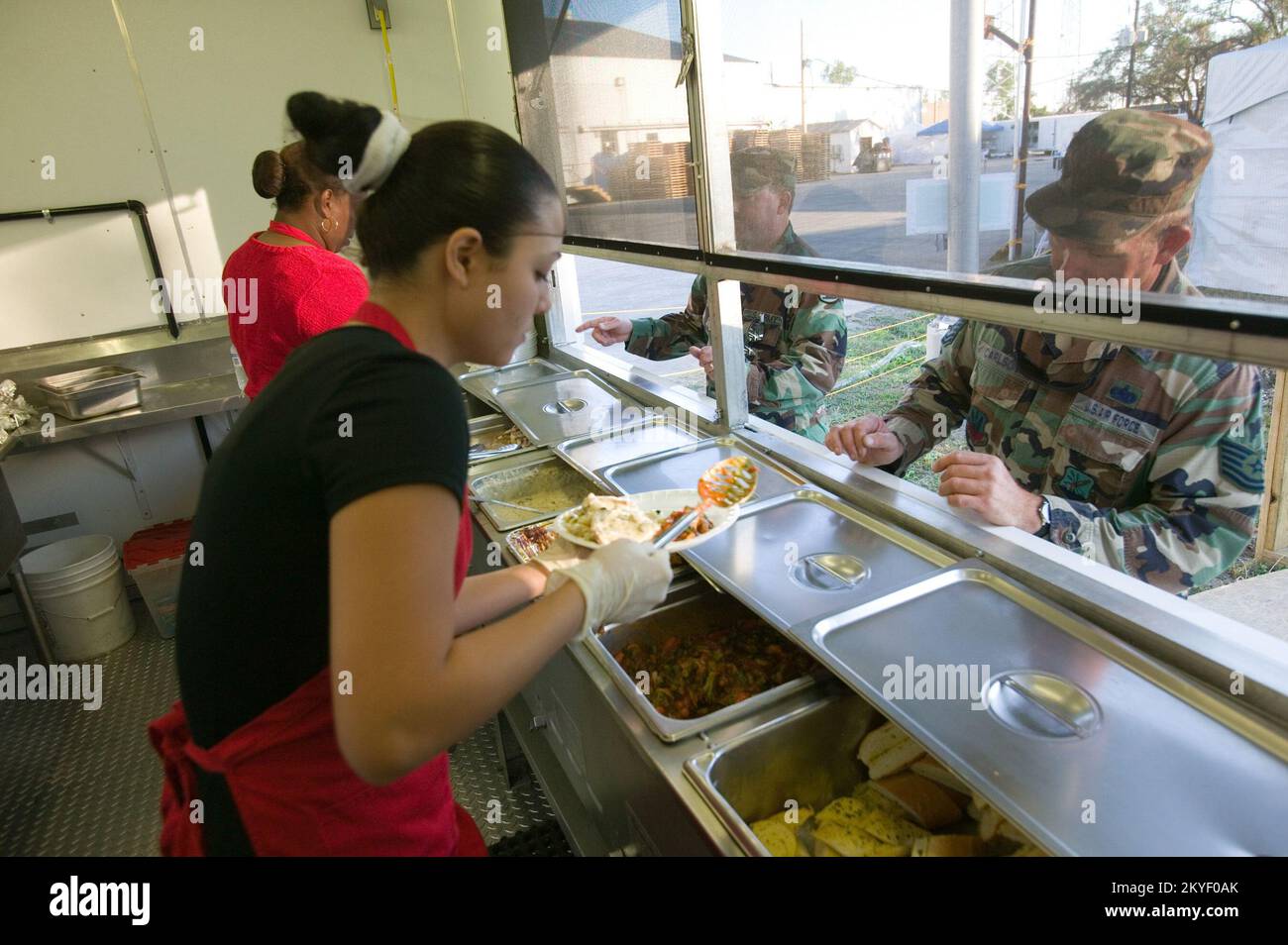 Uragano Katrina, New Orleans, LA, 10/29/2005 -- i lavoratori dei servizi di catering per incidenti preparano e servono la cena ai membri della Guardia Nazionale al campo base di Plaquemines. I campi base sono allestiti per fornire alloggi temporanei ai militari e agli operatori di emergenza in seguito all'uragano Katrina. Foto FEMA/Andrea Booher Foto Stock