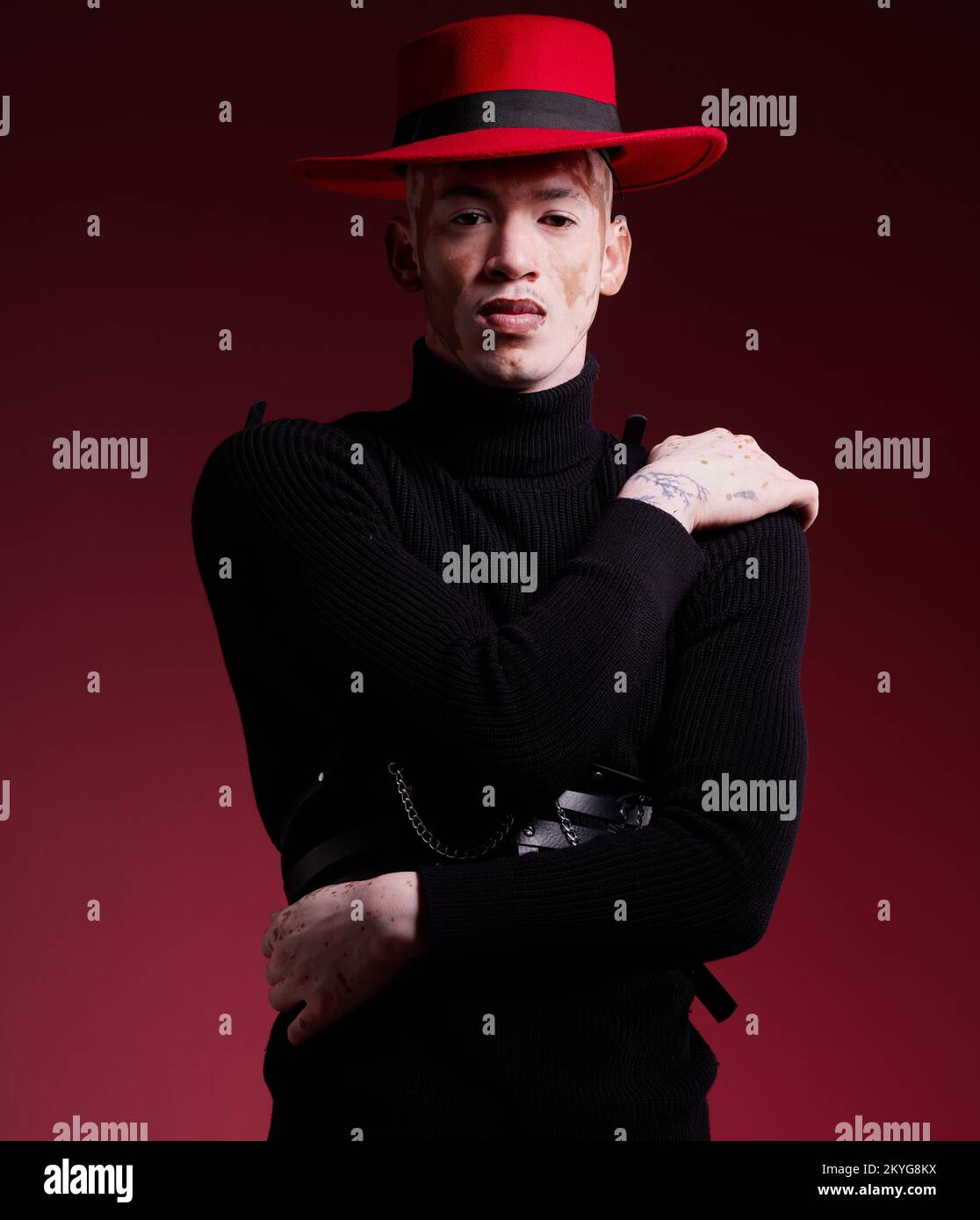 Moda, estetica e ritratto dell'uomo su sfondo rosso con stile, bellezza e cosmetici di design in studio. Creativo, arte e modello maschile con Foto Stock