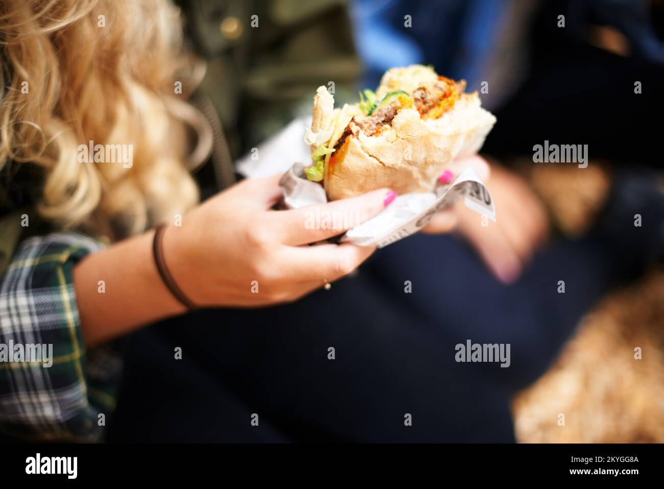 Energia per il festival musicale. Una giovane ragazza che tiene un hamburger a un festival di musica. Foto Stock