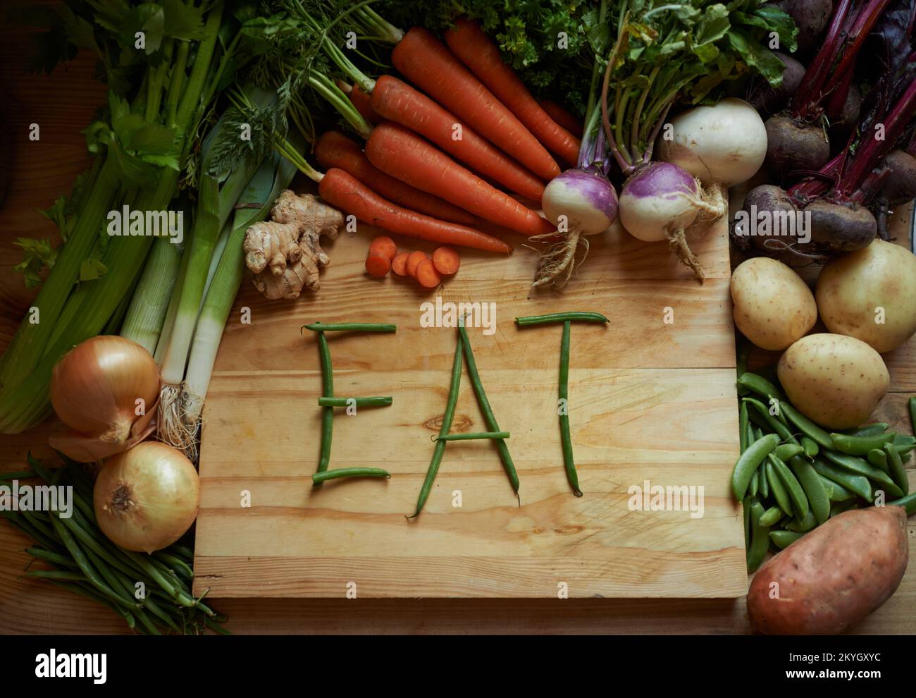 Fresco dalla terra. Ancora vita ripresa di una varietà di verdure su un tagliere con il messaggio mangiare. Foto Stock Fresco dalla terra. Ancora vita ripresa di una varietà di verdure su un tagliere con il messaggio mangiare. Foto Stock