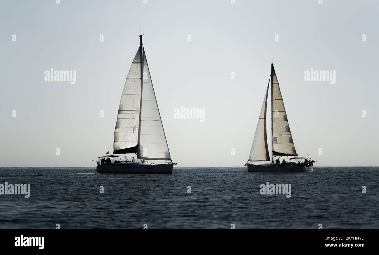 Due navi a vela che attraversano l'oceano contro il cielo bianco Foto Stock