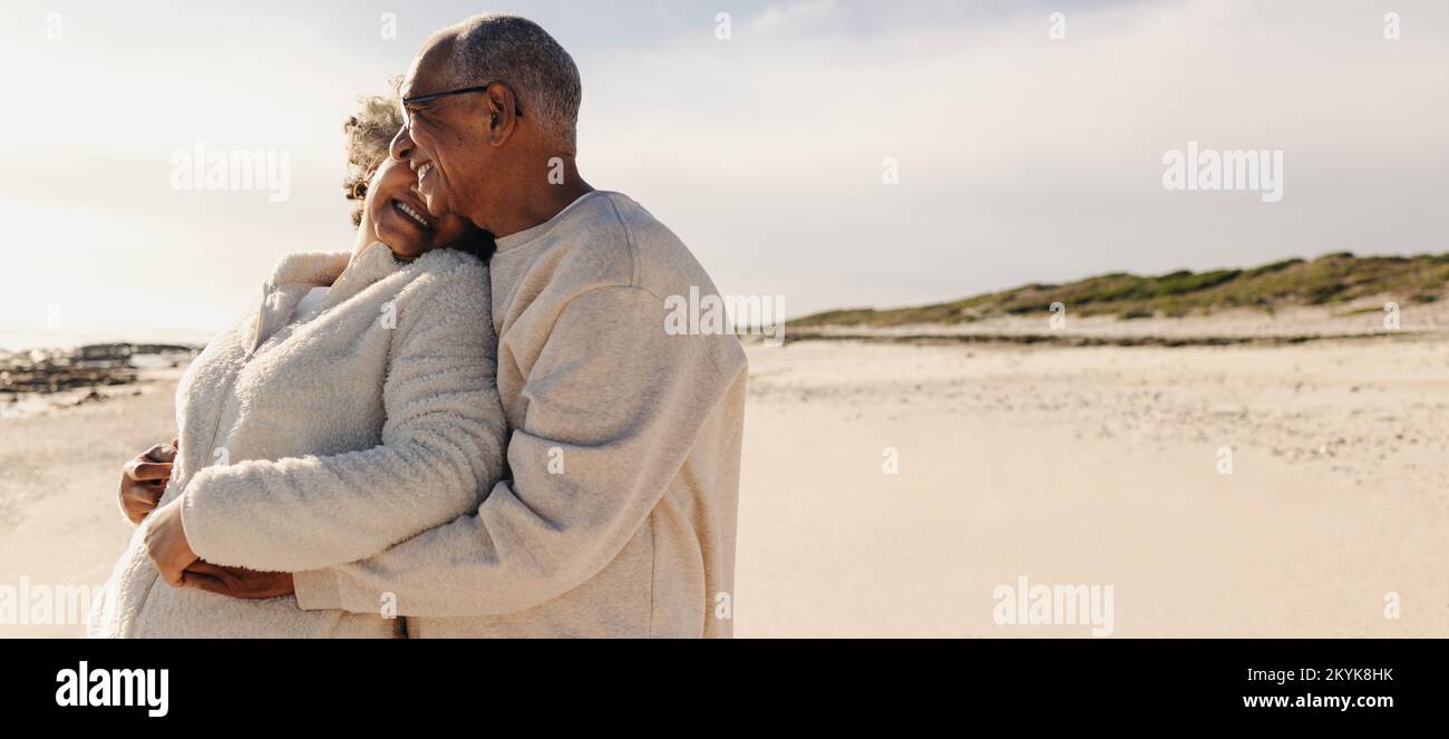 Innamorarsi della spiaggia. Felice coppia anziana sorridente e abbracciante mentre si trova in piedi sulla spiaggia di sabbia. Coppia anziana allegra godendo thei Foto Stock