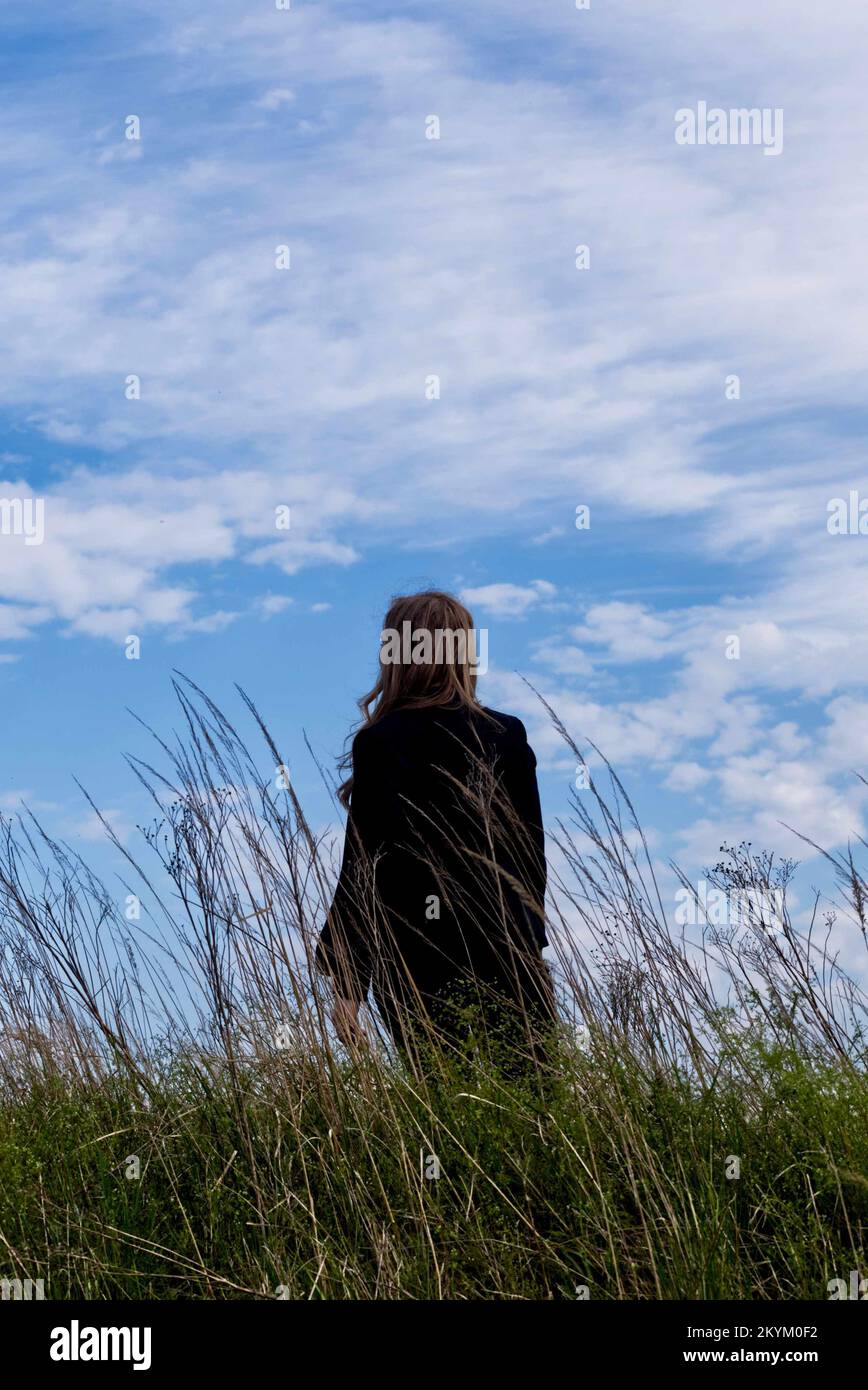 donna in tuta con pistola in piedi nel log grass. stile copertina libro a distanza media. Foto Stock