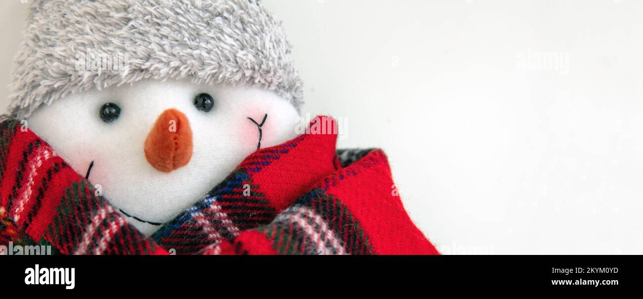 Buon pupazzo di neve con sciarpa rossa su sfondo bianco, vista ravvicinata, spazio copia. Modello di biglietto di auguri per le festività natalizie. Foto Stock