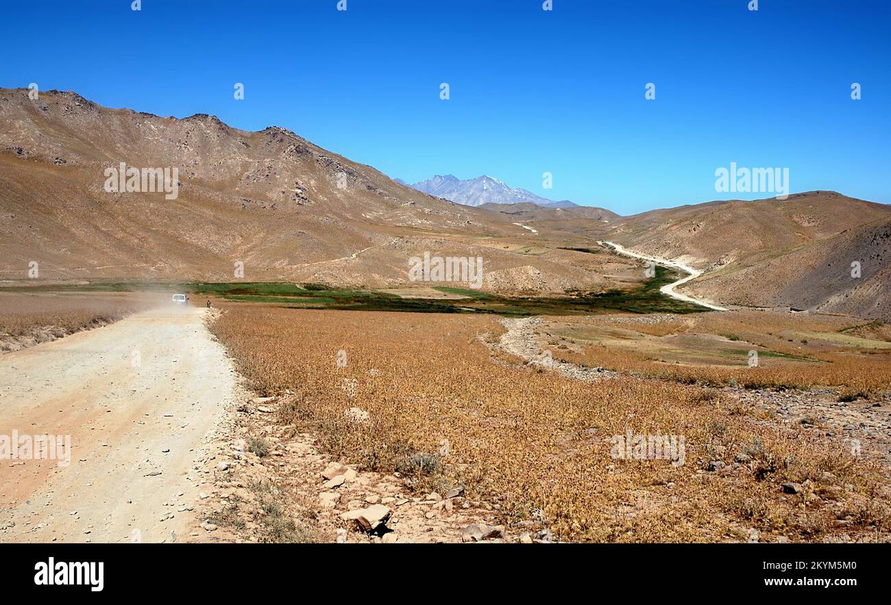 Scenario tra Kabul e Bamyan (Bamiyan) in Afghanistan. Strada polverosa attraverso il paesaggio montano sulla strada meridionale tra le due città. Foto Stock