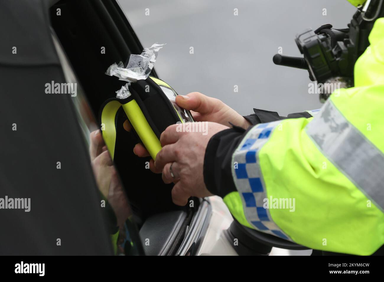 Un poliziotto che guarda un respiratore al lancio della polizia invernale 2022/23 anti-drink / droga guida operazione su Sydenham Road a Belfast. Data immagine: Giovedì 1 dicembre 2022. Foto Stock
