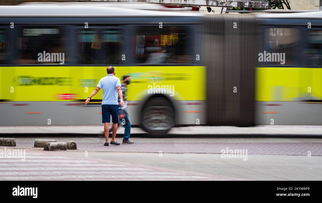 Uomini che attraversano una strada vicino a un autobus in movimento a Belo Horizonte, Minas Gerais, Brasile. Foto Stock