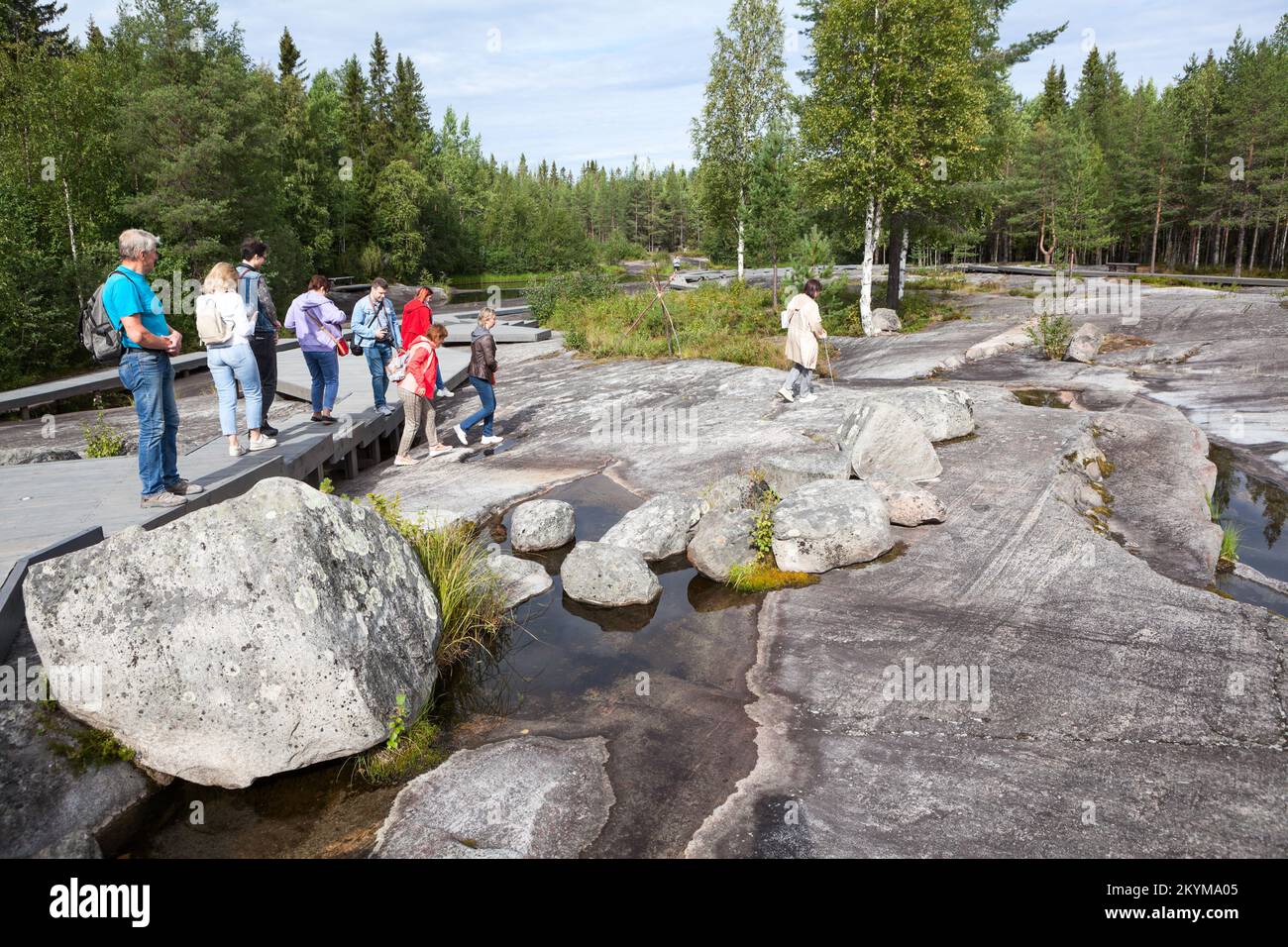 Zalavruga, Belomorsk città, Repubblica di Carelia, Russia-circa ago, 2022: Gruppo di turisti con una guida si trova in zona del complesso archeologico con t Foto Stock