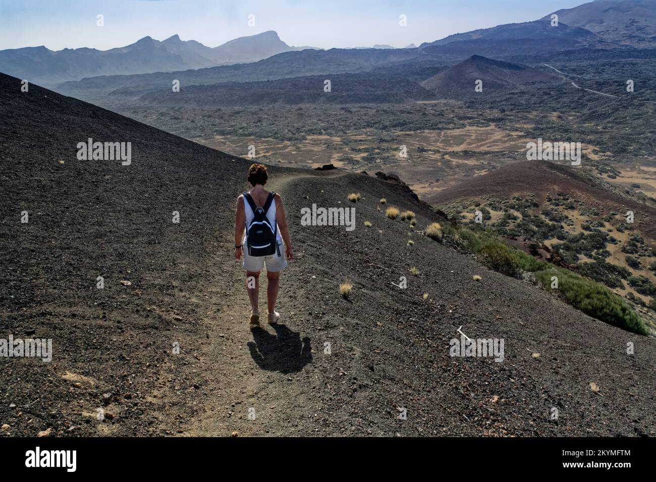 Donna che cammina su un sentiero sul cono di cenere vulcanica nera del Montana de las Arenas Negras, Parco Nazionale del Monte Teide, Tenerife, Isole Canarie, ottobre Foto Stock