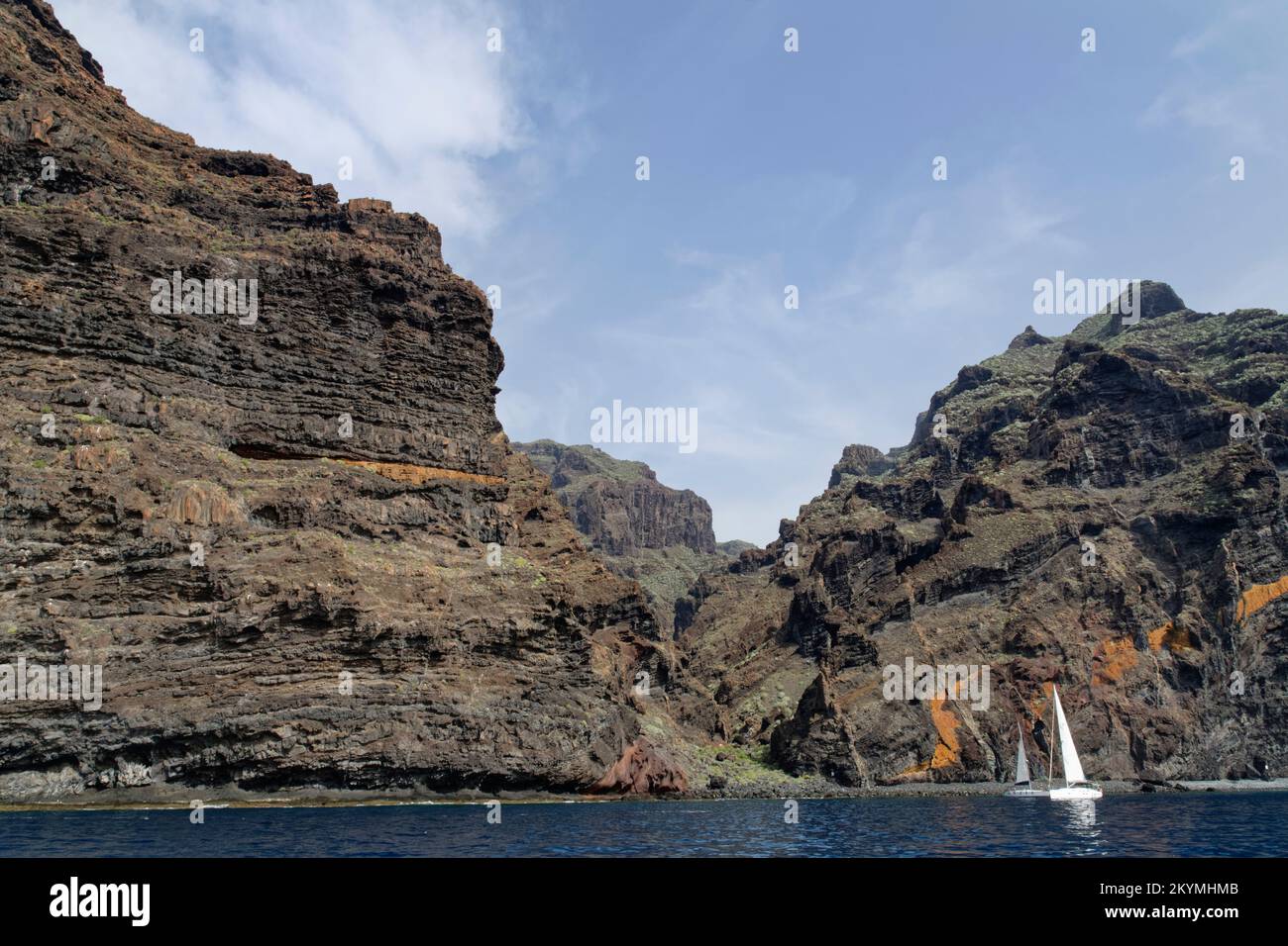 Barche a vela ormeggiate sotto i 500 metri di altezza 'Acantilados de Los Gigantes' scogliere vulcaniche, Tenerife, Isole Canarie, Spagna, ottobre. Foto Stock