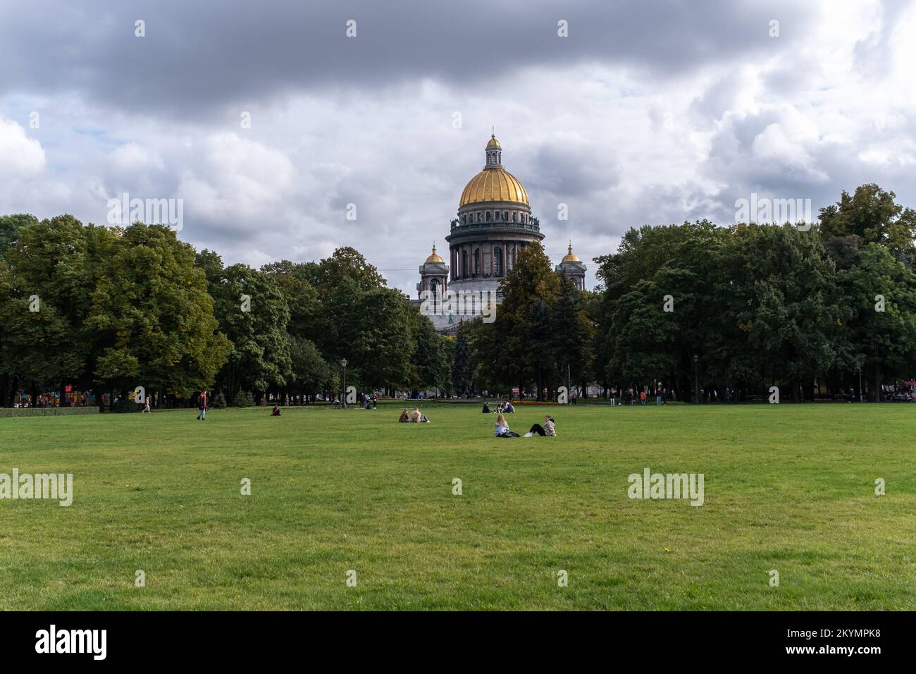 La gente è seduta sul prato vicino alla Cattedrale di San Isacco, punto di riferimento in St. Petersburg, Russia. Foto Stock