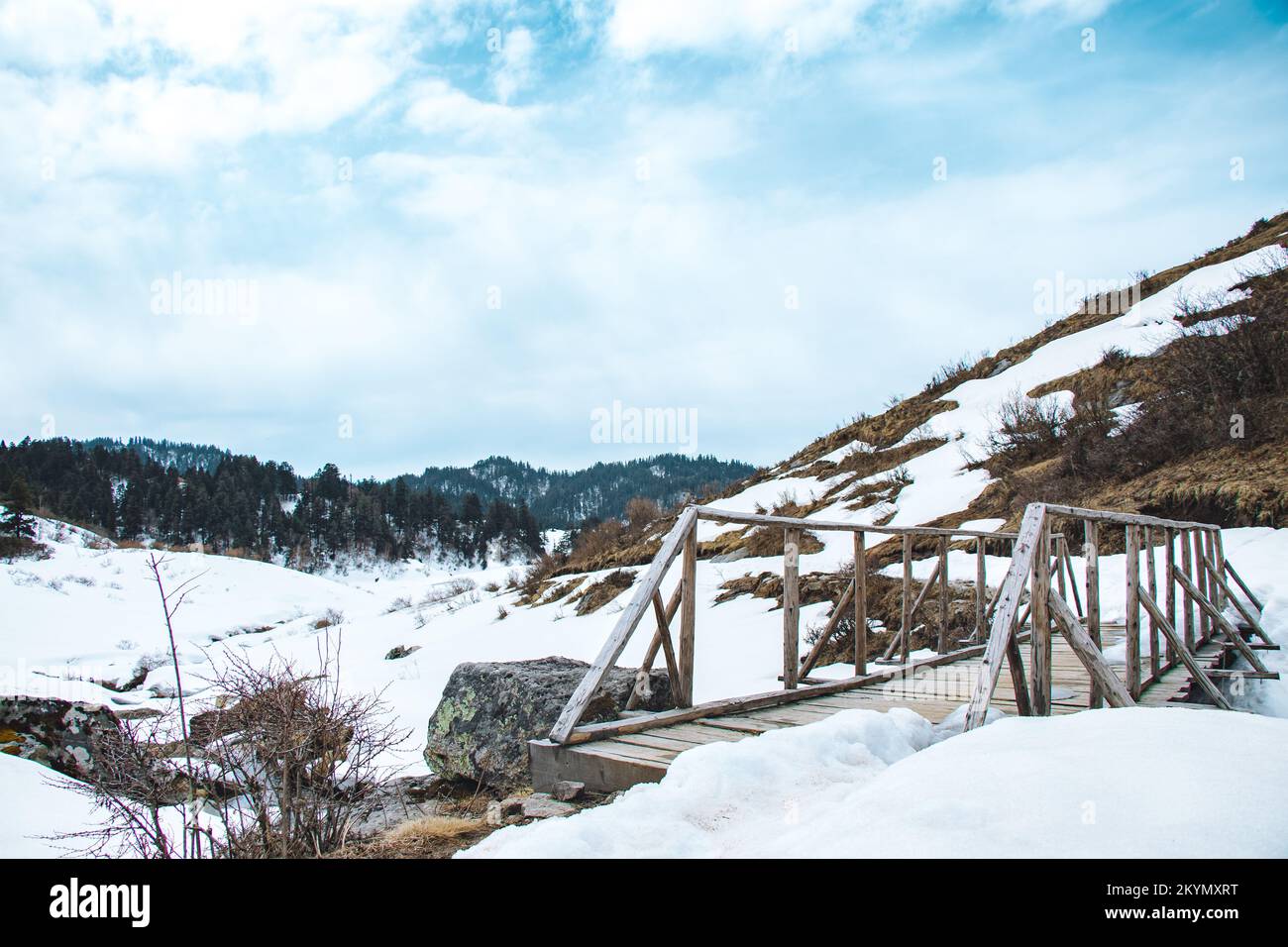 Bel ponte in legno sulle montagne innevate dell'Himalayas Nepal Kaptad National Park Foto Stock