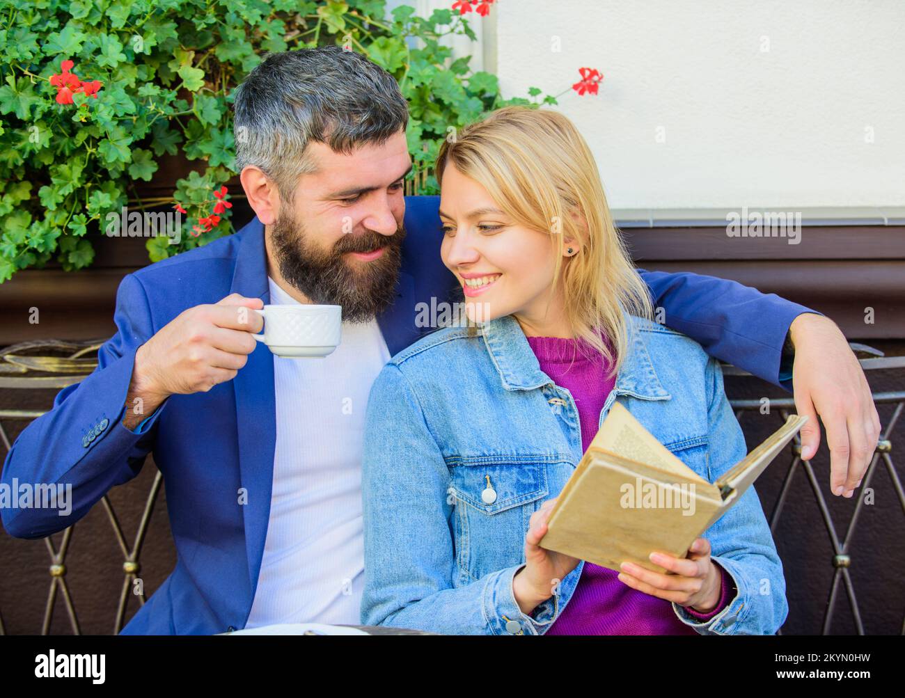 Interessi comuni. Coppia innamorata, sit cafe Terrace. Uomo con barba e donna bionda coccole sulla data romantica. Concetto romantico. Coppia flirting romantico Foto Stock