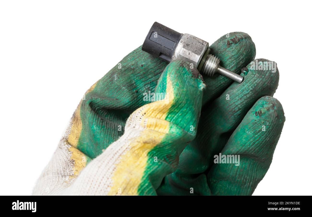 Sensore di pressione dell'olio dell'automobile isolato su fondo bianco nel braccio nel guanto del meccanico. catalogo ricambi. Foto Stock