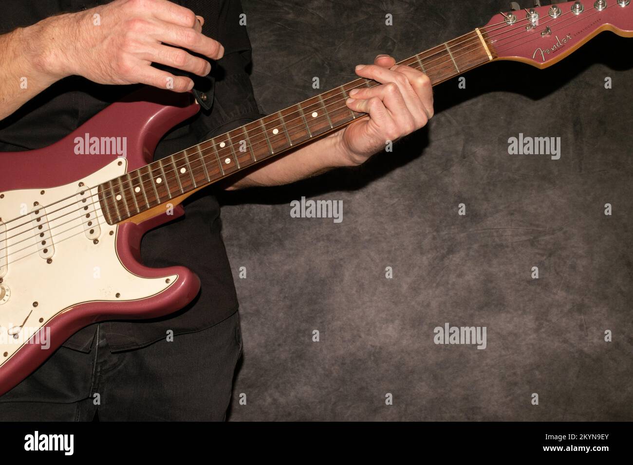 Vaduz, Liechtenstein, 11 gennaio 2022 il musicista suona un Fender Stratocaster USA realizzato 1995 nel colore della nebbia di borgogna Foto Stock