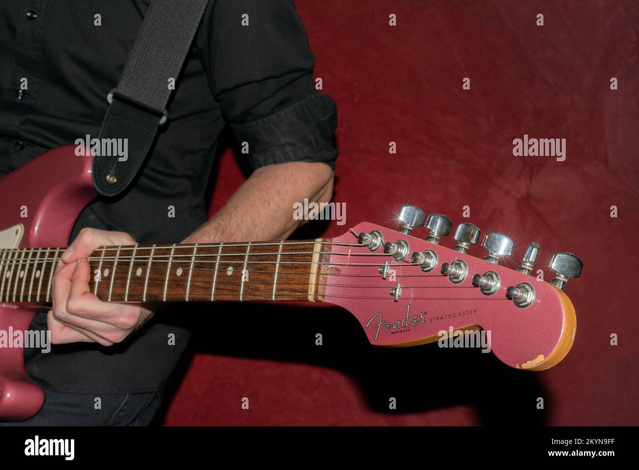 Vaduz, Liechtenstein, 11 gennaio 2022 il musicista suona un Fender Stratocaster USA realizzato 1995 nel colore della nebbia di borgogna Foto Stock