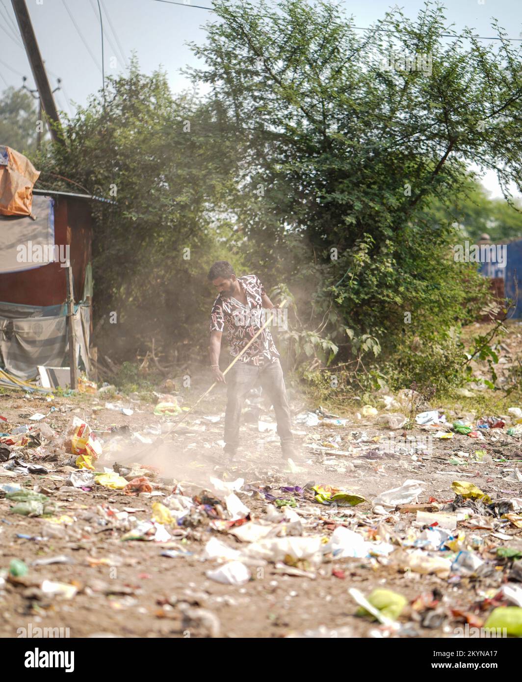 Uomo spazzare i rifiuti con spazzatrice e polihthene grande spazzatura zona, uomo pulire la zona inquinata, controllo dell'inquinamento giorno, concetto di inquinamento Foto Stock