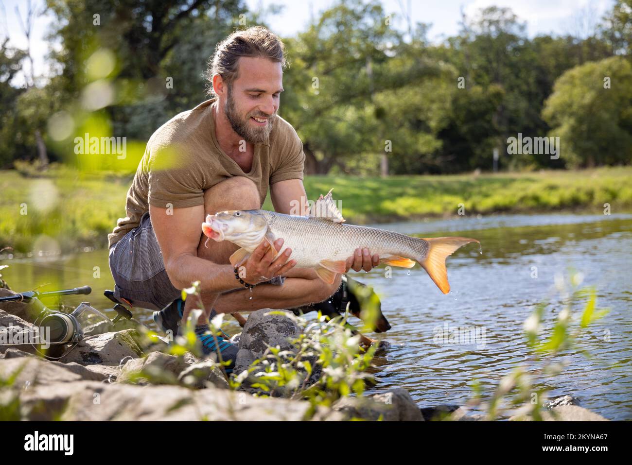 Il pescatore di hobby riuscito ha interferito un pesce in un fiume Foto Stock