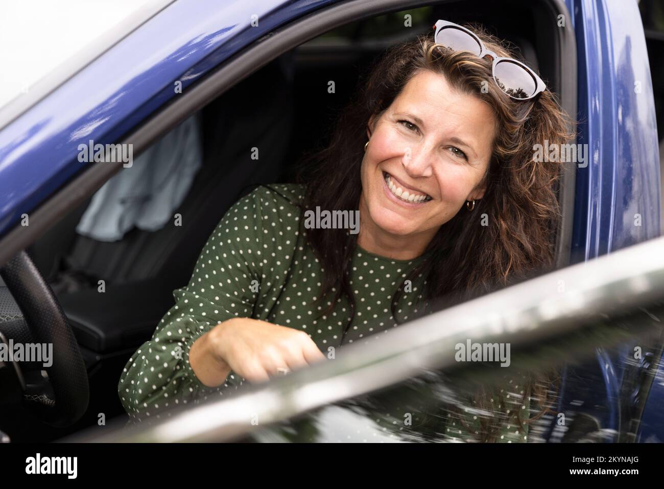 Ritratto di donna felice con occhiali da sole seduti in auto Foto Stock