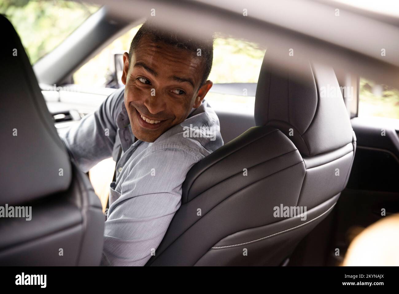 Uomo felice che guarda dietro la spalla mentre si siede in auto Foto Stock
