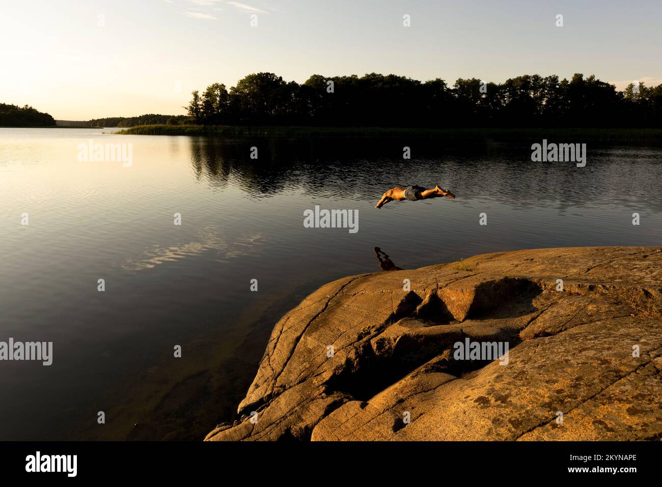 Uomo che si tuffa in lago durante le vacanze al tramonto Foto Stock