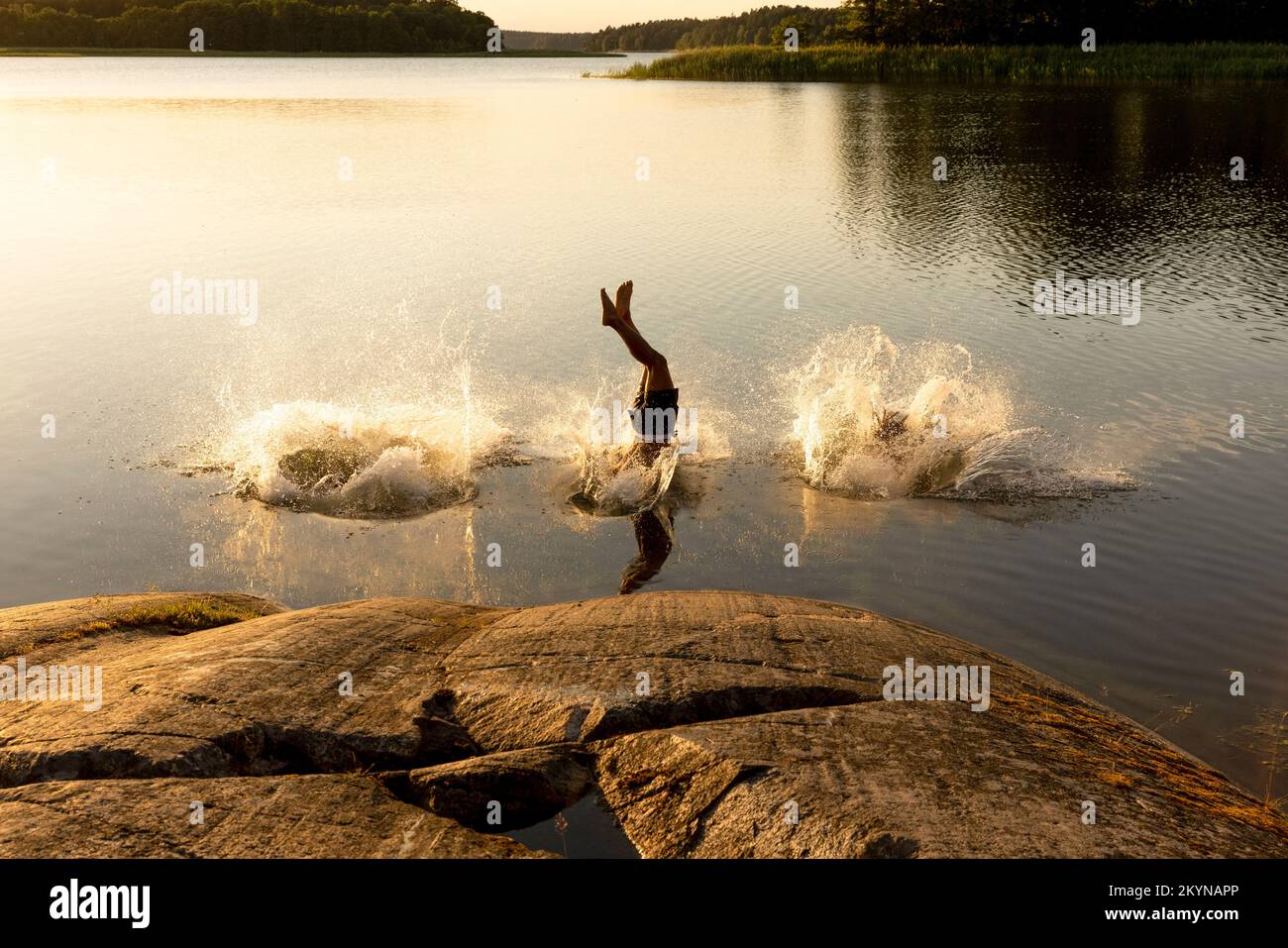 Uomo che tuffa e spruzzi d'acqua nel lago al tramonto Foto Stock