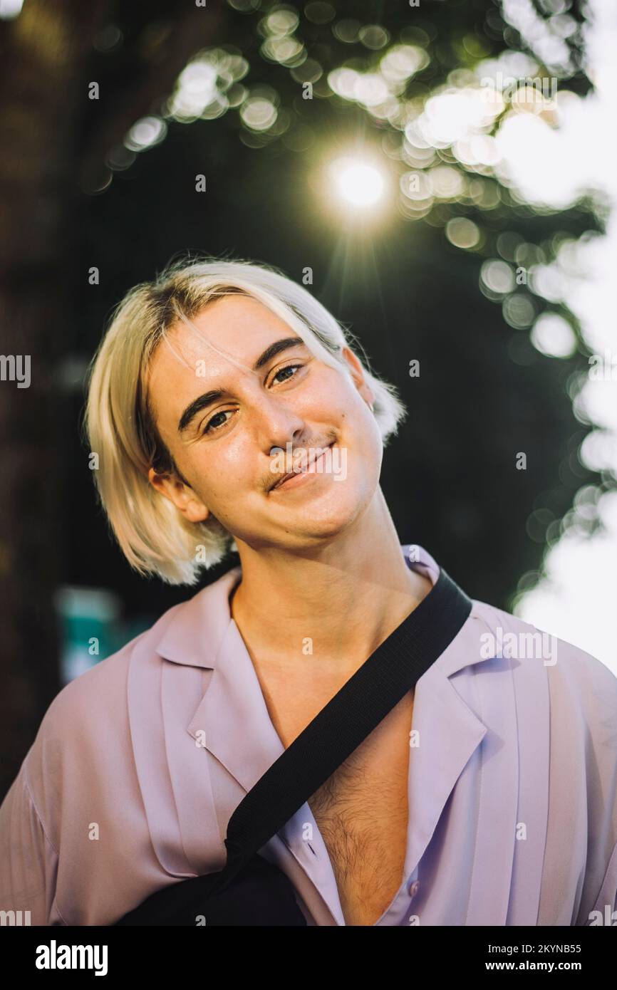Ritratto di una persona sorridente non binaria con capelli biondi Foto Stock