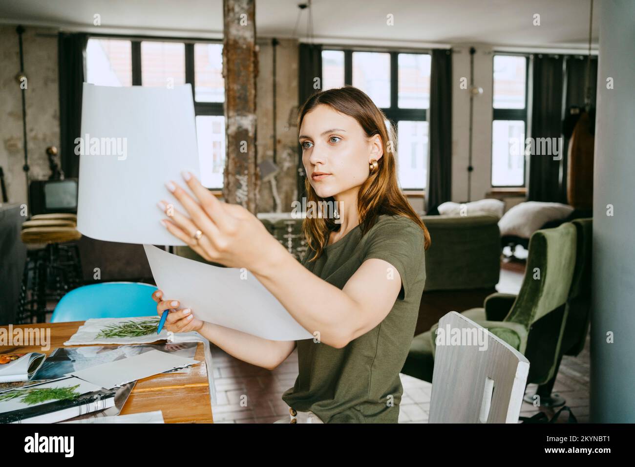 Giovane imprenditrice che confronta le fotografie a tavola in studio Foto Stock