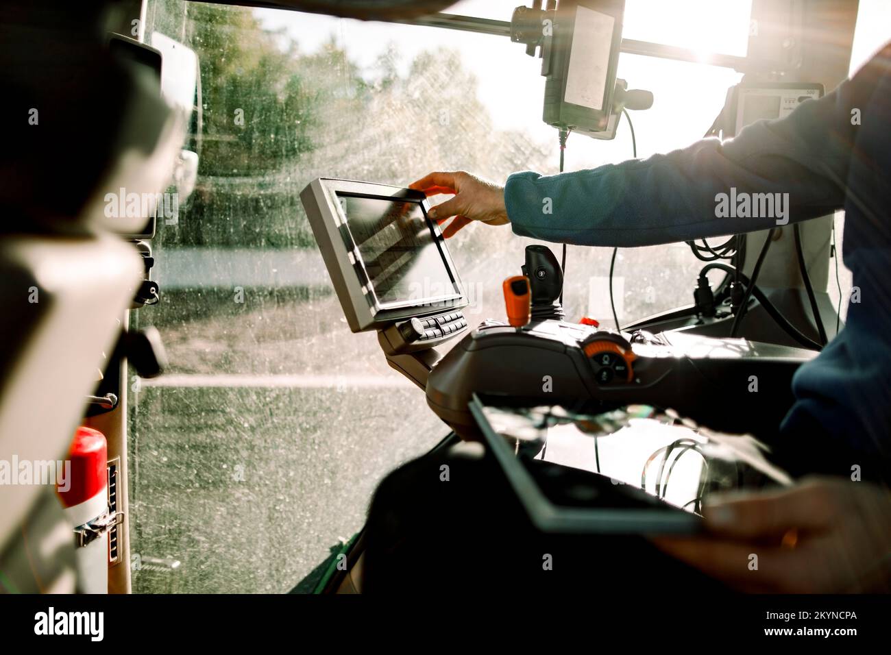 Mano del contadino che utilizza il computer seduto sul trattore nella giornata di sole Foto Stock