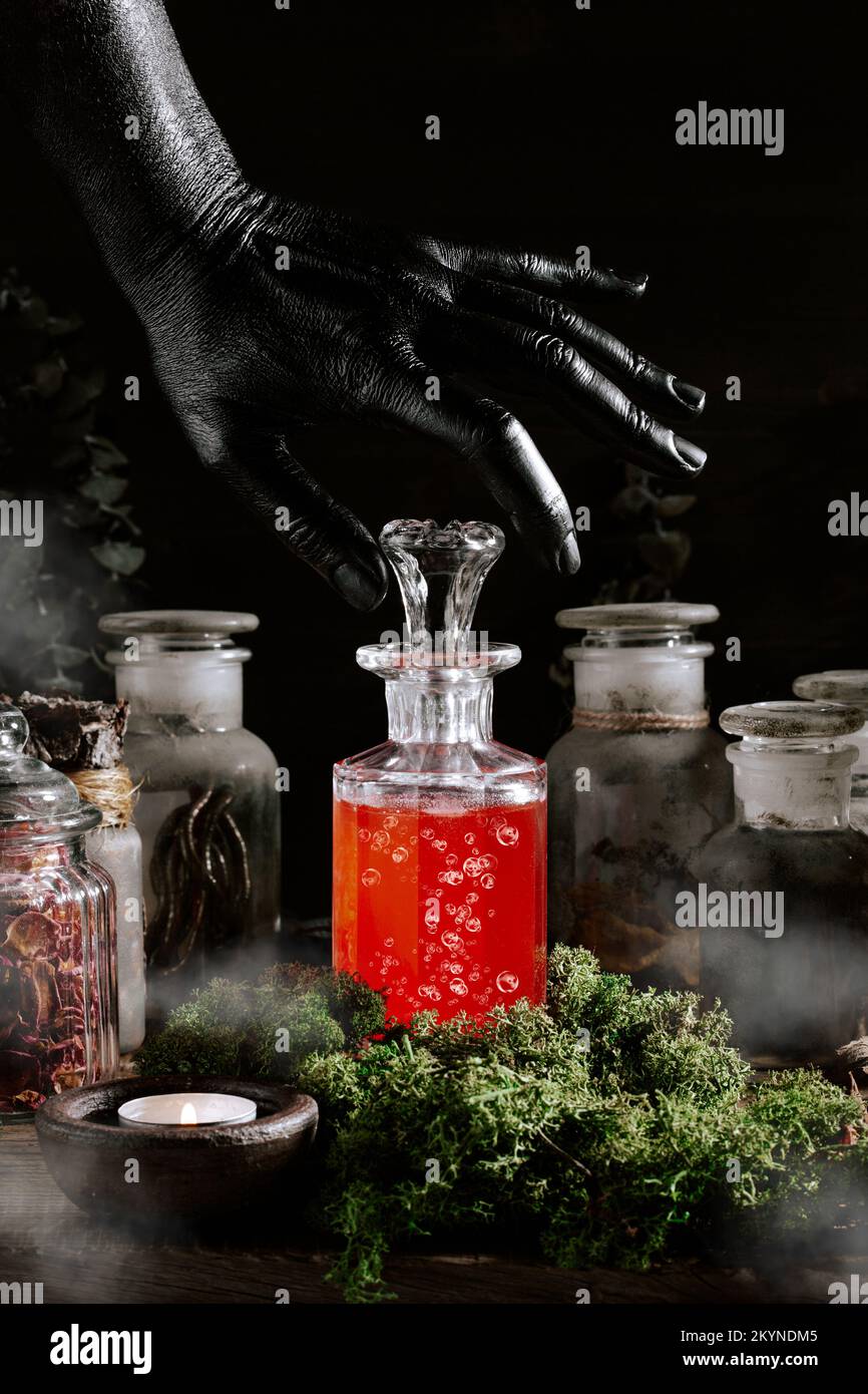 strega nera mano apertura pozione magica, erbe ingredienti candele e attrezzatura magica Foto Stock