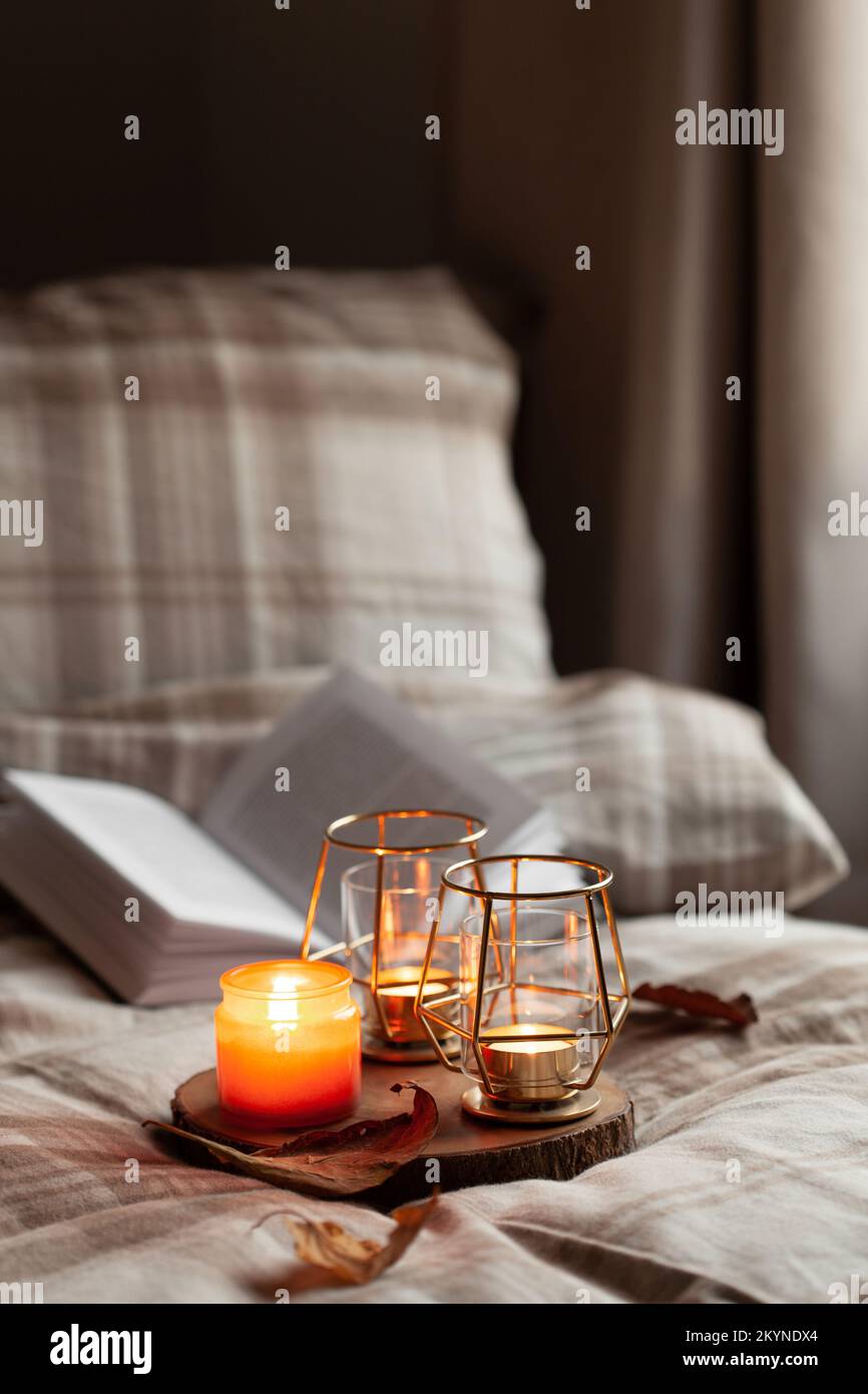 calda camera accogliente inverno o autunno concetto, candele su vassoio e un libro Foto Stock