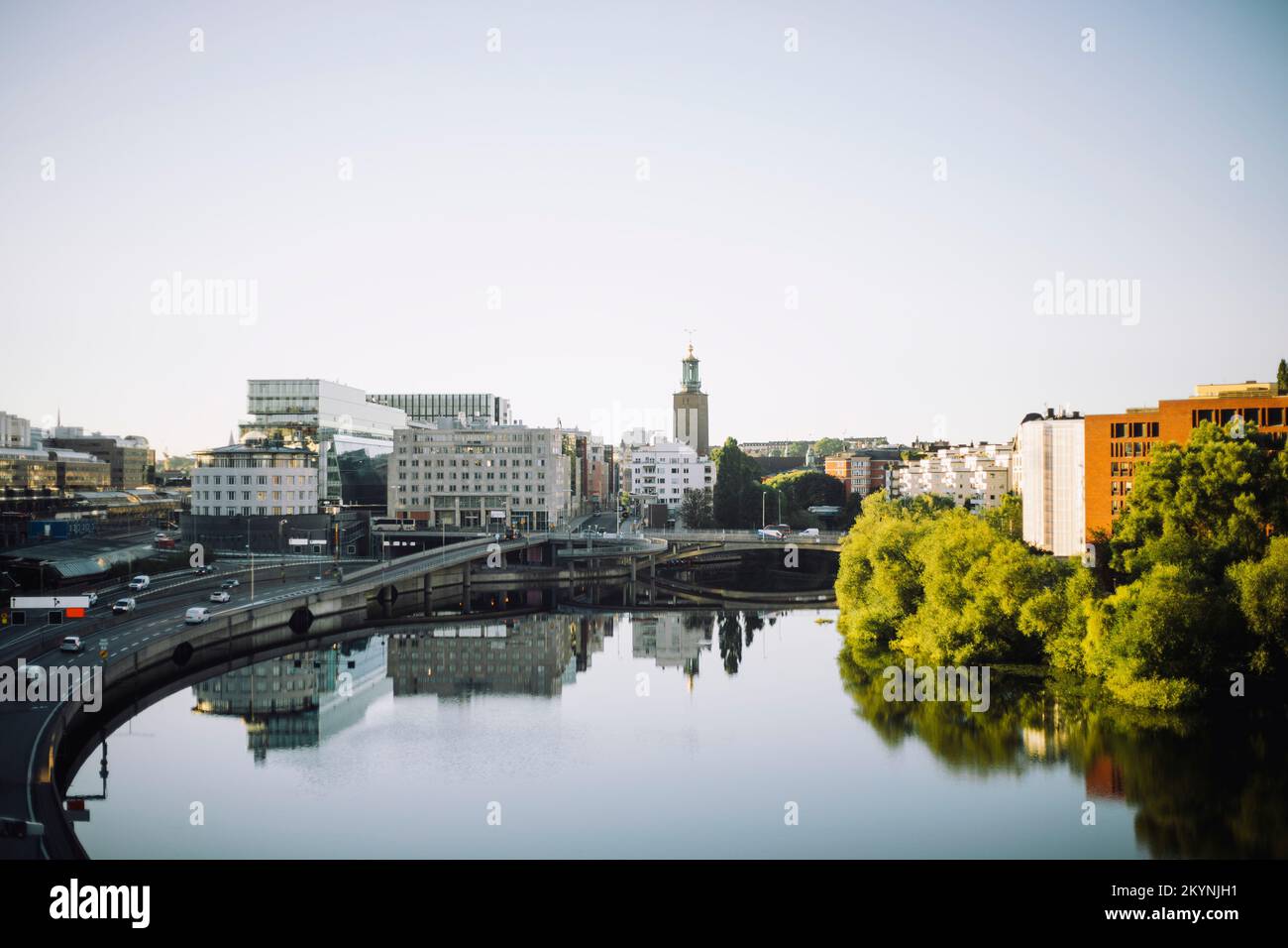 Il Municipio di Kungsholmen è circondato da edifici moderni che si riflettono nel mare contro il cielo limpido Foto Stock