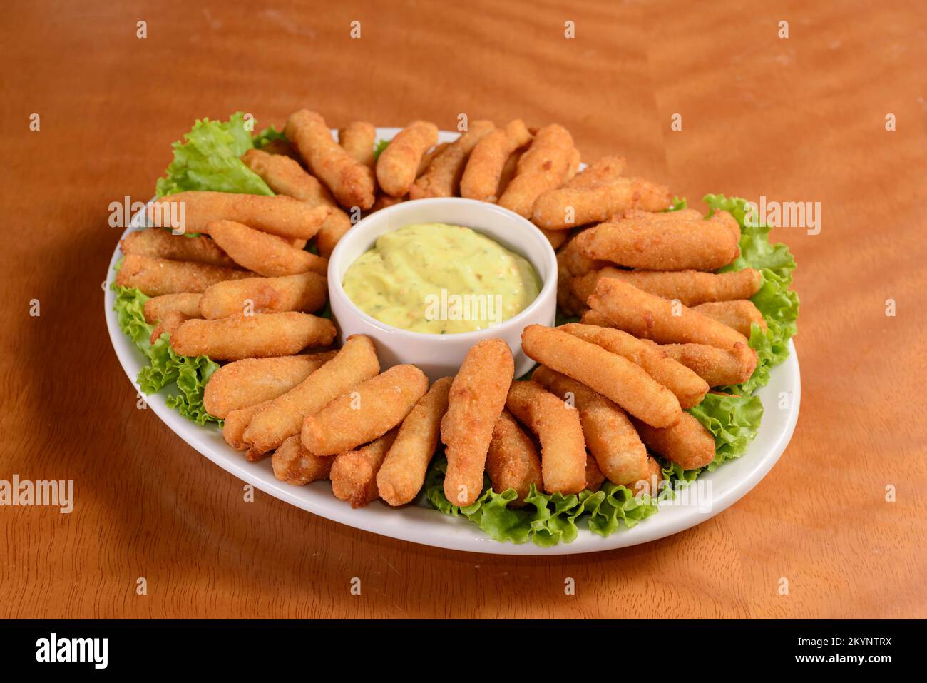 Torta di pesce con salsa tartara sfondo di legno. Spuntino brasiliano. Foto Stock
