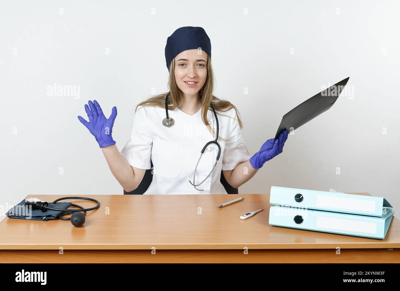 Medicina e concetto di salute. Una giovane e stanca dottoressa emozionalmente ondeggia una cartella di note. Isolato su sfondo bianco. Foto Stock