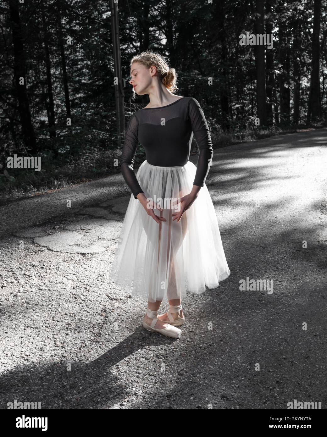 Una giovane ballerina si trova in una posizione ballerina sulla strada Foto Stock