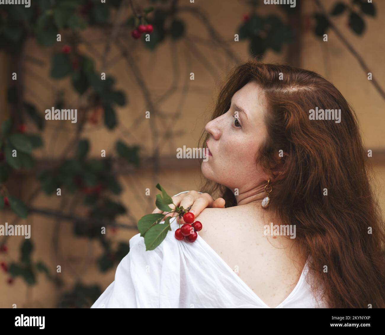 Ritratto di una giovane donna con un rametto di bacche di ciliegia Foto Stock