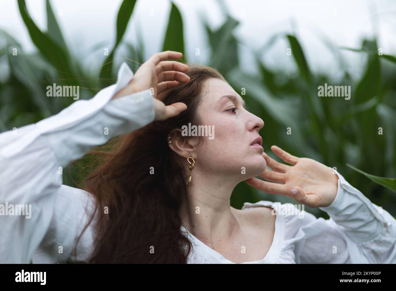 Ritratto di una giovane donna in un campo di grano con le mani in su Foto Stock